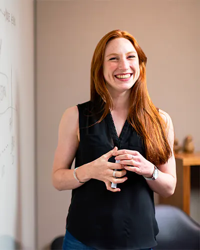 woman teaching about cost savings on a white board smiling